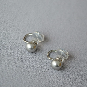 Détail de boucles d'oreilles clips perles grises avec coussinets sur fond minimaliste