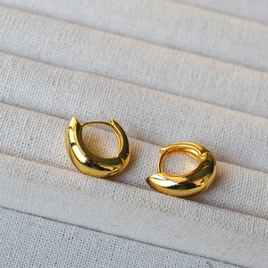 Polished gold-plated hoop earrings in teardrop shape on textured display box