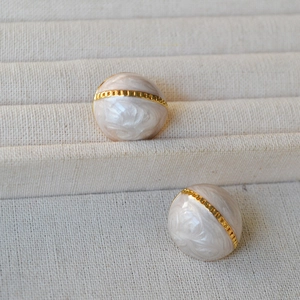 Détail macro des boucles d'oreilles demi-cercle en émail rétro avec bandes dorées