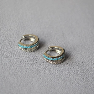 Macro detail of silver-tone hoop earrings with turquoise stones and cubic zirconia pavé