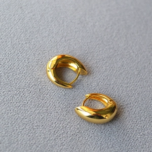 Close-up of polished thick gold hoop earrings with a sleek minimalist curved design