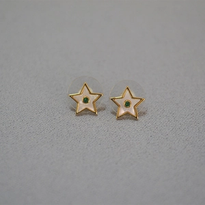Détails des boucles d'oreilles étoiles dorées avec émail blanc et pierres vertes