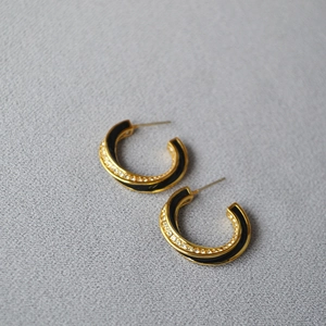 Detail of gold-plated Mobius hoop earrings with black enamel and white zircons