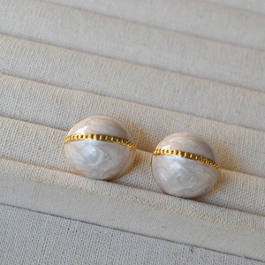 Boucles d'oreilles vintage en émail blanc demi-rond avec motif doré sur plateau à bijoux