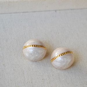 Vue macro de boucles d'oreilles rétro en émail avec bande dorée sur lin doux