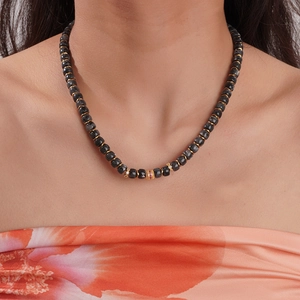 Macro detail of natural stone beaded necklace with 18K gold plated charms and red gems