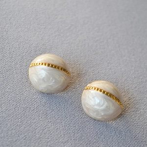 Gros plan sur les boucles d'oreilles émaillées blanches avec chaîne dorée vintage