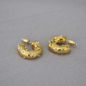Detailed view of chunky C-shaped brass earrings with gold plating and cubic zirconia