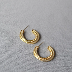 Detail of Mobius earrings with white enamel and sparkling zircon on gold finish