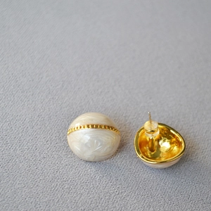 Détails macro de boucles d'oreilles émail blanc, bande dorée texturée et tiges en argent 925