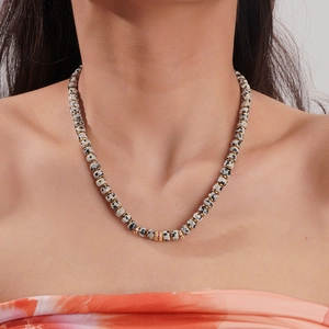 Close-up of 18K gold plated necklace featuring dalmatian jasper beads and red crystal