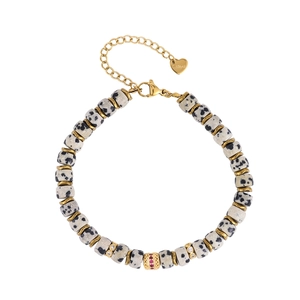 Detail of gold stainless steel bracelet with spotted natural stone beads and heart charm