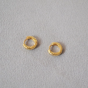 Close-up of gold-plated brass hoop earrings with unique hammered texture and matte finish