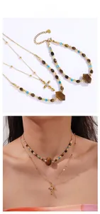 Détail du collier bohème avec perles œil de tigre et pendentif croix dorée en set
