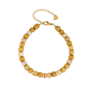 Detail of beaded bracelet with gold spacers, central red gemstone and heart charm tag