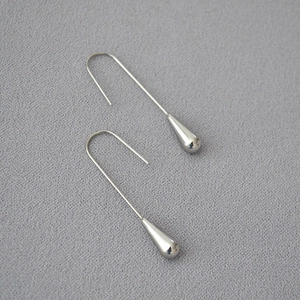 Polished silver teardrop earrings with long hook design on a dark textured background