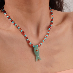 Gros plan d'un collier de perles rouges bohème avec pendentif poisson en aventurine