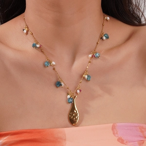 Détail du collier en acier doré avec pendentif poisson et perles de couleurs variées
