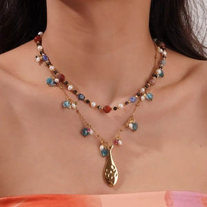 Détail de collier bohème doré avec perles, pierres colorées et pendentif en goutte