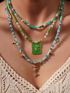 Detail of layered necklace with turquoise stones, evil eye beads, and mermaid charm pendant