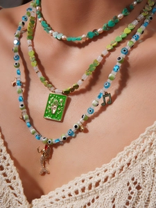 Detail of layered turquoise beaded necklace with evil eye pendants and mermaid charm