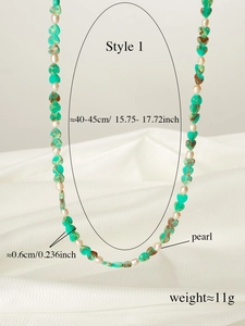 Detail of beaded necklace with green heart stones and white pearls on silk background