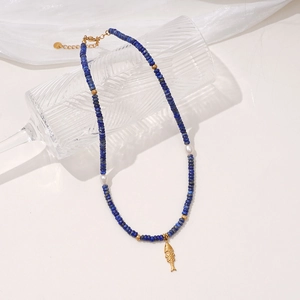 Collier en lapis-lazuli avec pendentif poisson doré sur fond de tissu blanc