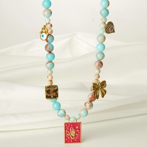 Détail d'un collier de perles ethnique avec main de Hamsa et breloques sur soie