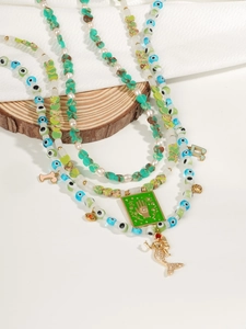 Detail of bohemian layered necklace with turquoise beads, hamsa charm and mermaid tail pendant