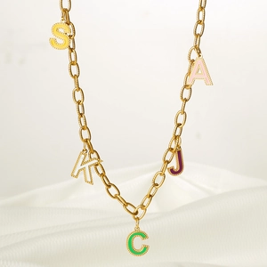 Détail d'un collier chaîne dorée avec pendentifs lettres S, K, C, J, A en émail coloré