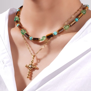 Collana doppia dorata con perline occhio di tigre e croce indossata da una modella