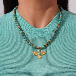 Gros plan du pendentif aigle doré avec turquoise sur un collier de perles marbrées