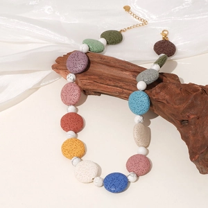 Collier bohème avec perles de lave colorées et turquoise blanche sur fond de bois