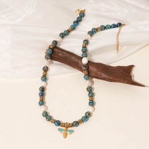 Vintage ketting met zebrasteen en parels met gouden bijenhanger op een rustieke achtergrond