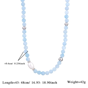 Detail view of light blue beaded necklace with white baroque pearl and silver spacers