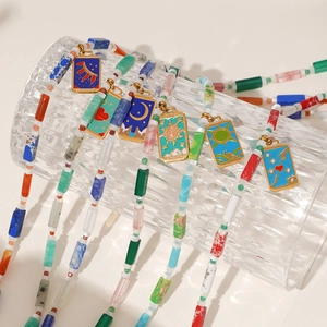 Close-up van kleurrijke kralenkettingen met gouden emaille tarot hangers op glaswerk