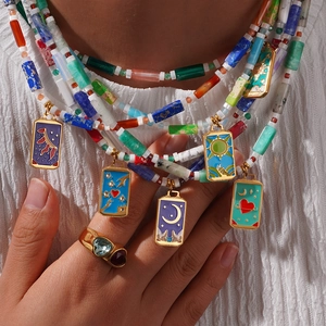 Kleurrijke natuursteen kralenketting met gouden tarot hangers op witte stoffen achtergrond