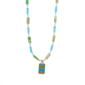 Detail van kralenketting met blauw-groene stenen en gouden zon tarot-stijl hanger