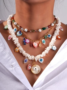 Macro view of layered bohemian necklaces featuring natural stone, devil eye and shell charms