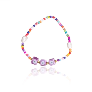 Detail of colorful bohemian beaded bracelet with freshwater pearls and evil eye charms