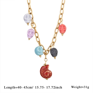 Detail of colorful gothic skull charms and red snail shell pendant on chunky gold chain