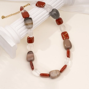 Detail of beaded necklace with red agate and quartz stones on white display