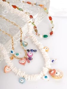 Detail of bohemian necklace featuring shell fragments, natural stone beads and evil eye charms