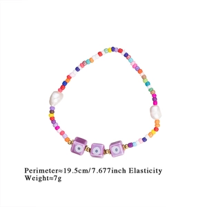 Colorful seed bead bracelet with white pearls and purple evil eye charms detail