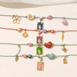 Detail of four colorful bohemian braided ropes with shells and Fatima hand charms
