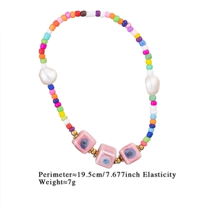 Detail of colorful seed bead elastic bracelet with evil eye beads and baroque pearls