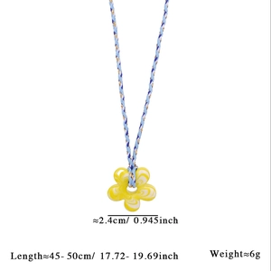 Détail du pendentif fleur en verre marbré jaune sur cordon tressé bicolore