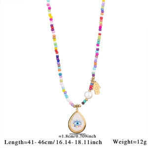 Detail of beaded necklace with Hamsa hand, pearl, and blue evil eye charms with dimensions