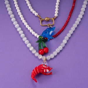 Nautical style necklaces with cat eye stones, dolphin and lobster charms on purple background