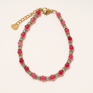 Détail de perles à facettes roses et grises avec pendentif cœur doré sur le collier